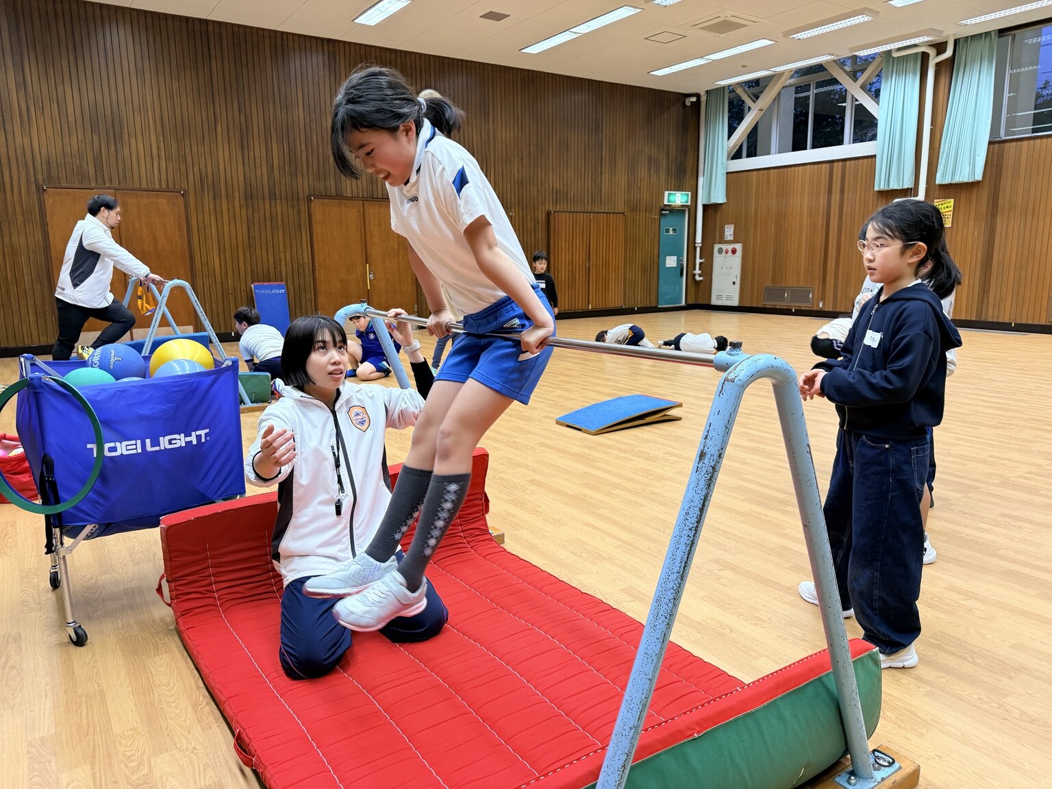 指導員が見守る中で子どもが鉄棒に取り組む体操指導